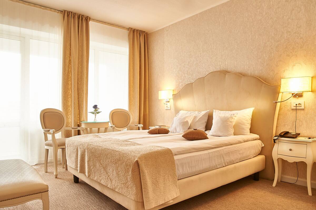 A hotel room with a large bed, two bedside tables, a desk, and a chair.