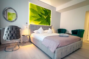 A modern bedroom with a large bed, a tufted armchair, and a green accent chair. - Hotel Continental Forum Arad (Arad)