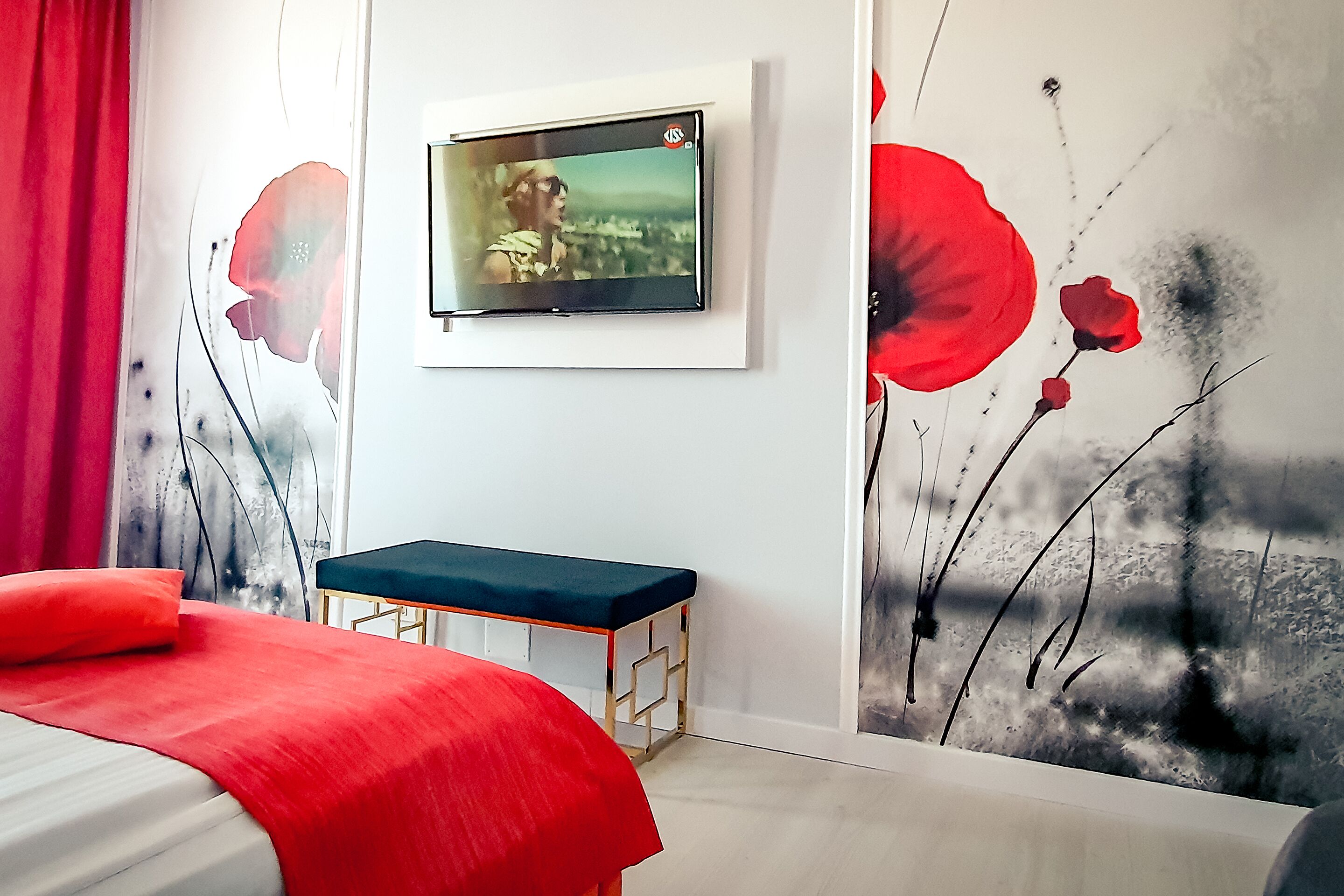 Un dormitorio moderno con una cama, un televisor montado en la pared y un mural de arte pop.