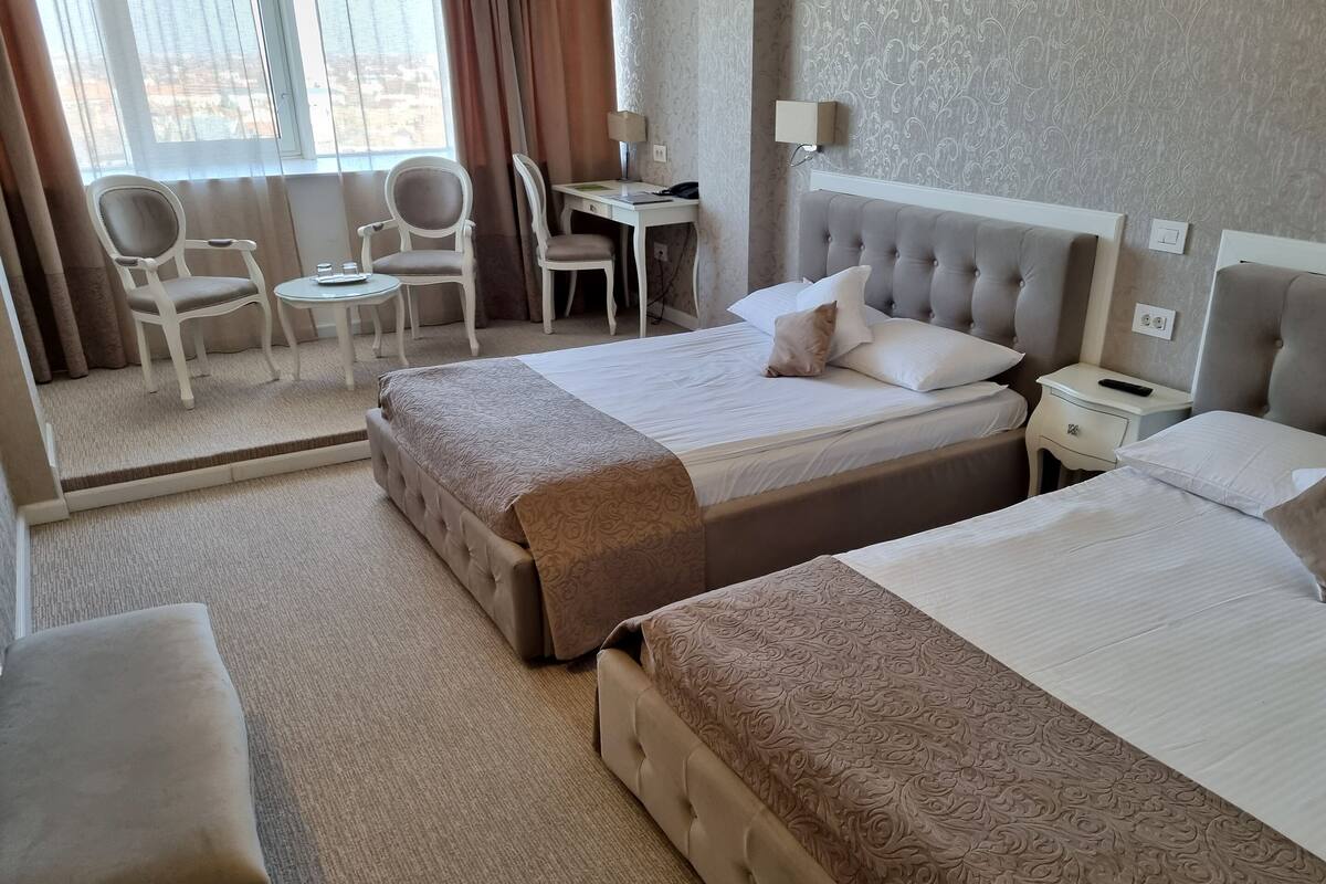 A hotel room with two beds, a desk, and chairs.