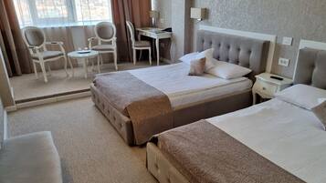 A hotel room with two beds, a desk, and chairs.
