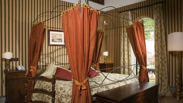 Ein Bett mit Himmelbett, ein Nachttisch aus Holz mit Lampe sowie ein Beistelltisch mit Lampe.