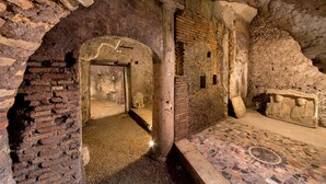 An ancient stone room with a mosaic floor, a brick column, and a stone relief. - The Inn at the Roman Forum Luxury Collection - The Inn At The Roman Forum (Rome)