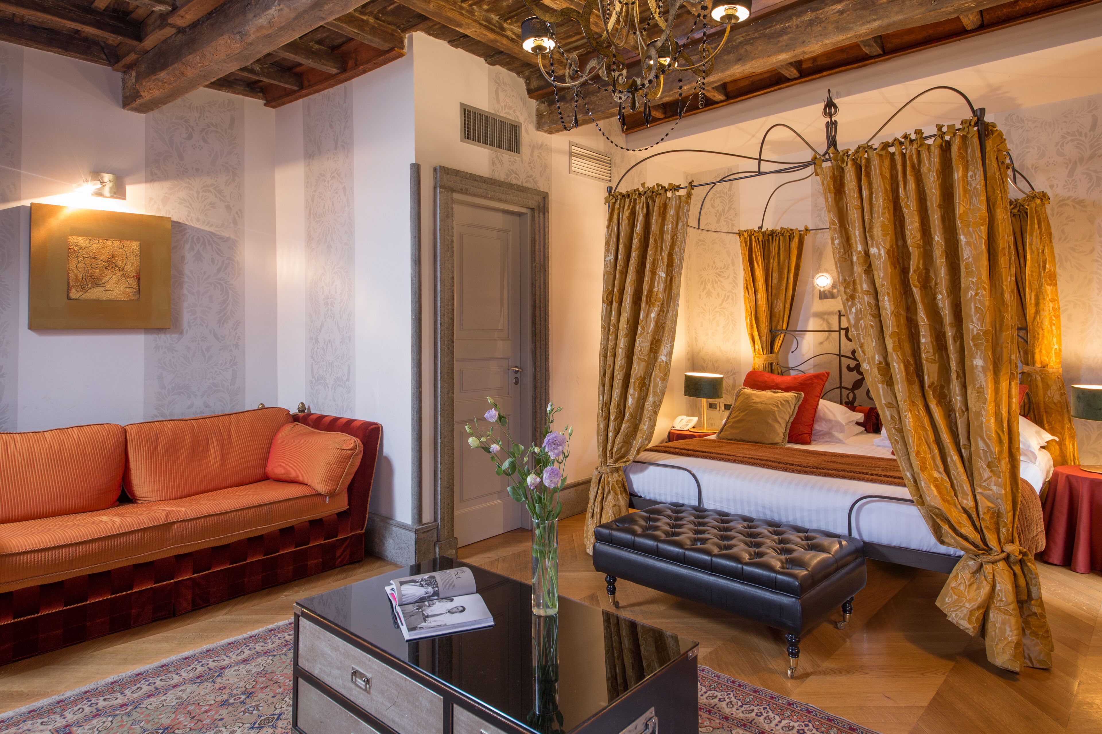Een hotelkamer met een bed, een slaapbank, een salontafel en een kroonluchter.
