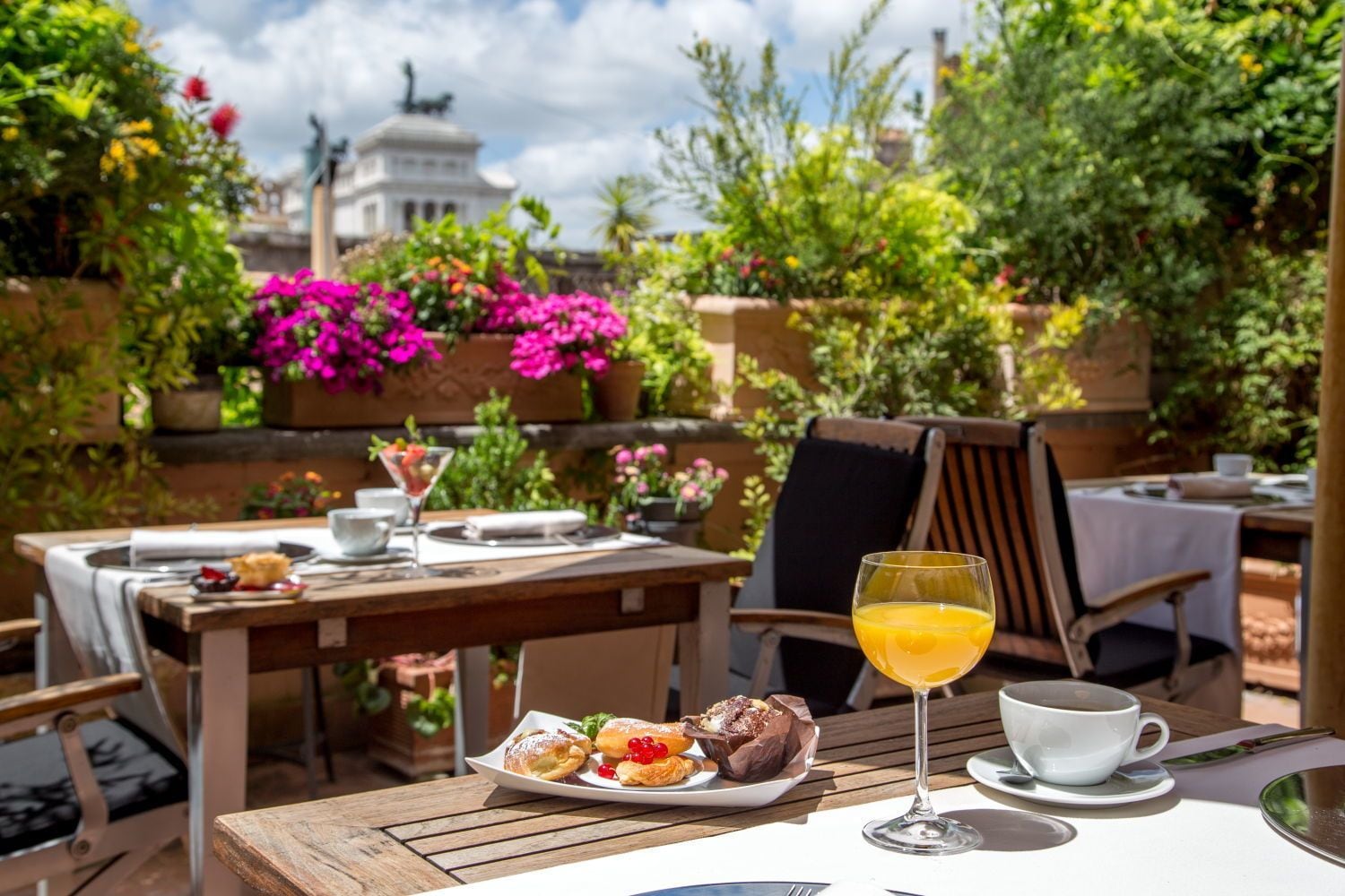 An outdoor dining area with tables, chairs, and a variety of food and drinks.