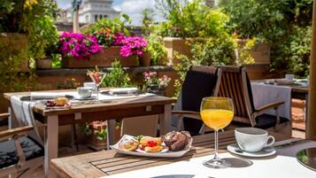 An outdoor dining area with tables, chairs, and a variety of food and drinks.