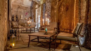 A rustic interior with stone walls, a wooden table, and a sofa. - The Inn at the Roman Forum Luxury Collection - The Inn At The Roman Forum (Rome)