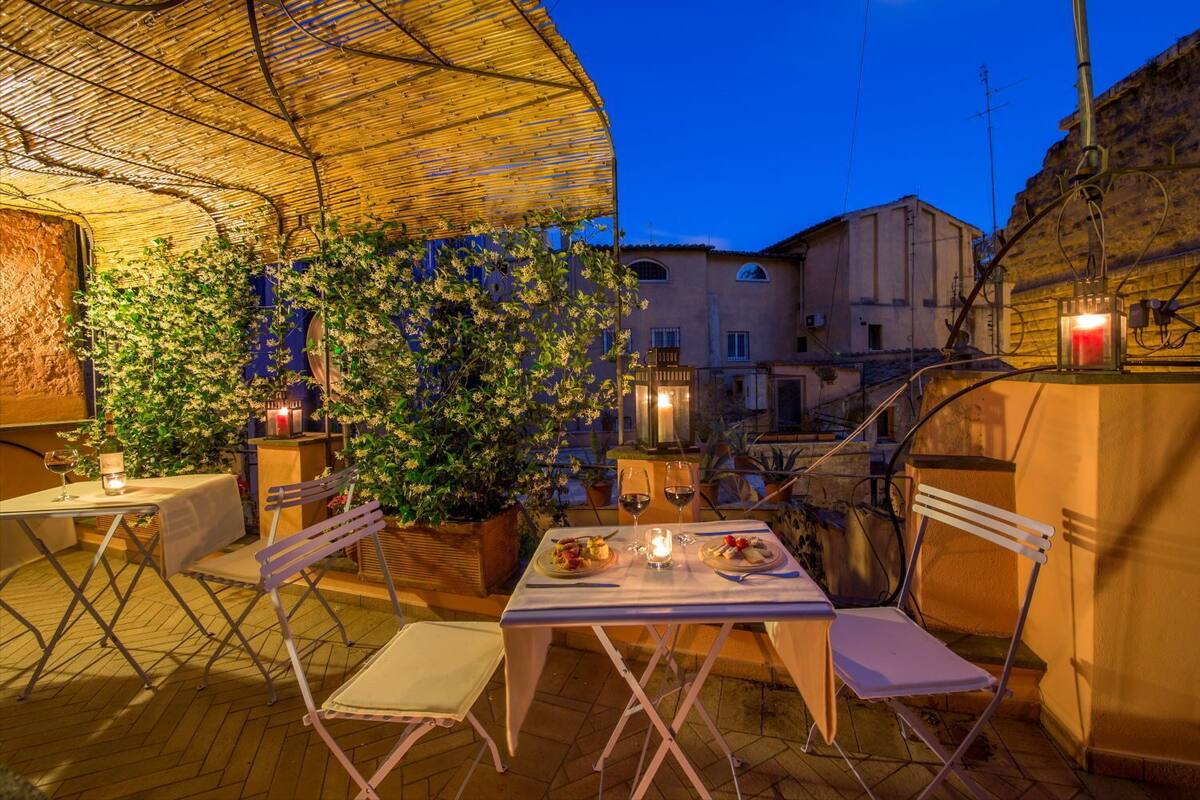 Un espace de restauration en plein air, avec des tables et des chaises, entouré de plantes et d’un mur de briques.