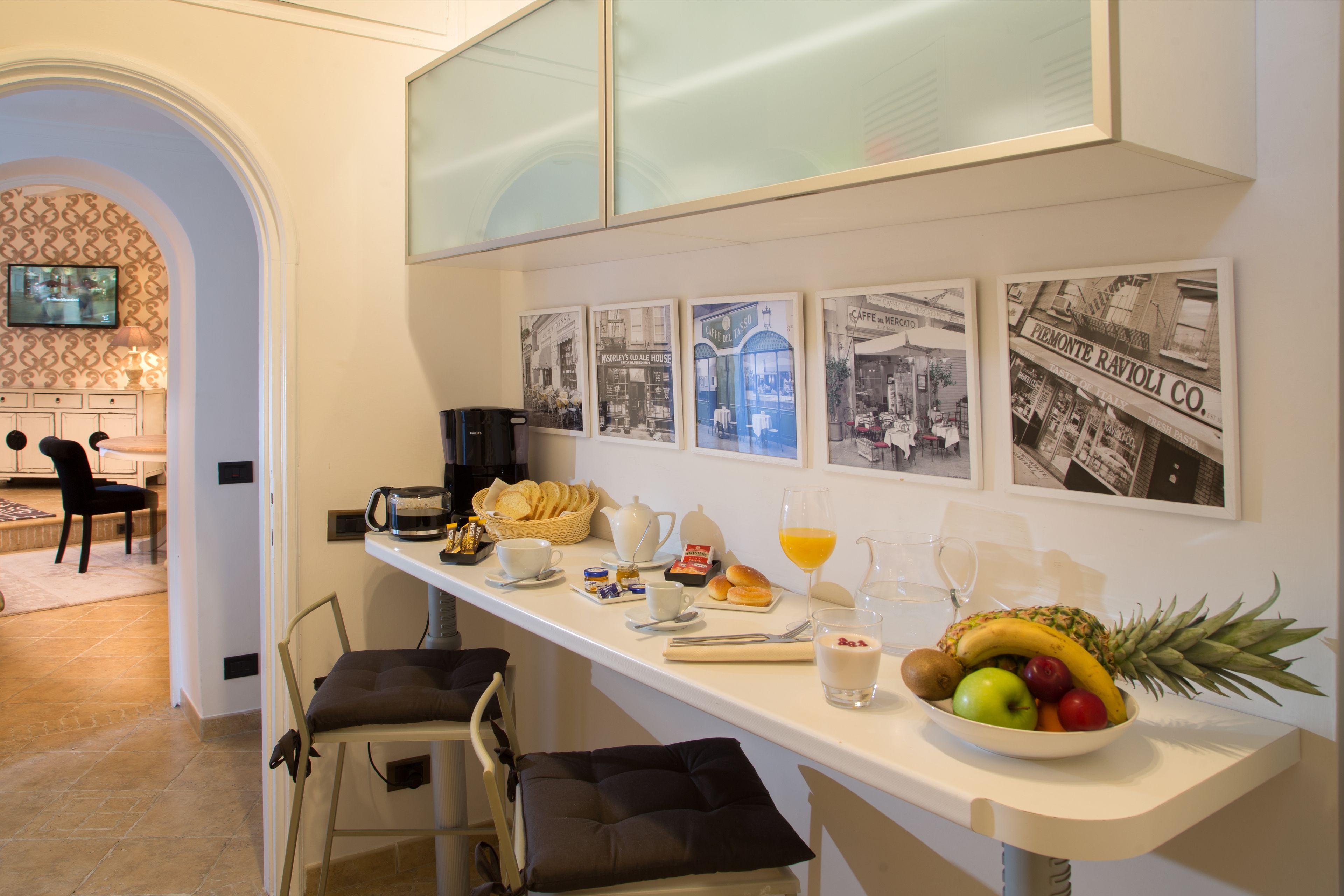 A breakfast bar with a bowl of fruit, coffee, and pastries.