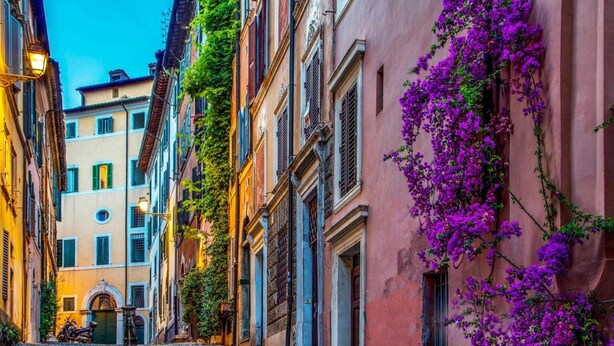 A narrow street with buildings on either side, featuring a staircase leading to a door. - The Inn at the Roman Forum Luxury Collection - The Inn At The Roman Forum (Rome)