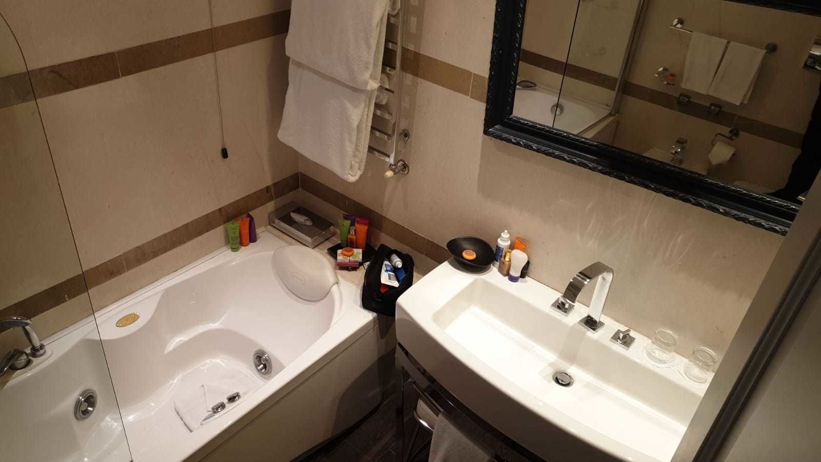 A bathroom with a bathtub, a sink, and a mirror.
