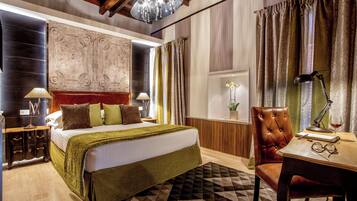 Une chambre à coucher avec un grand lit, un bureau en bois, un fauteuil en cuir et un lustre.