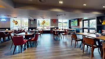 Un restaurant spacieux avec de hauts plafonds, de grandes fenêtres et différents types de sièges, notamment des tables et des chaises.