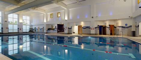 A large indoor swimming pool with clear lanes, a tiled floor, and a high ceiling with visible ductwork.