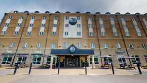 A multi-story building with a Village Inn sign, a Starbucks Coffee, and outdoor seating areas. - Village Hotel Bournemouth (Bournemouth)