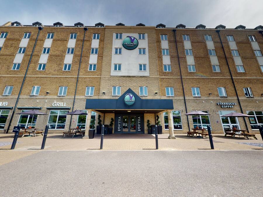 A multi-story building with a Village Inn sign, a Starbucks Coffee, and outdoor seating areas.