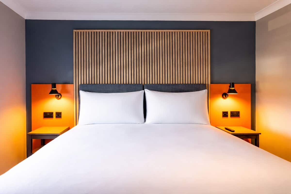 Ein modernes Hotelzimmer mit einem großen Bett, zwei Nachttischen und einem Holzkopfseitenverkleidung.
