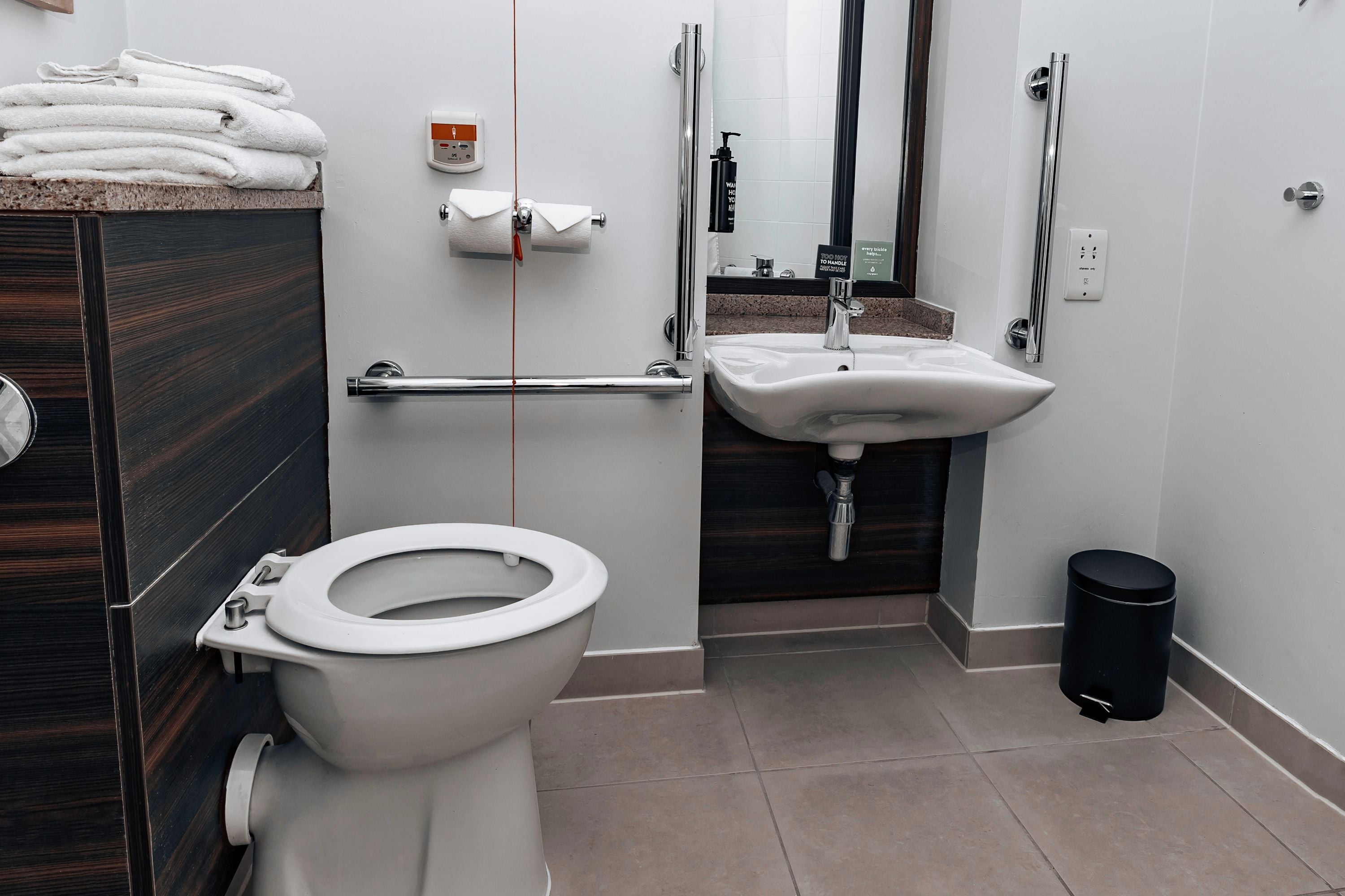 A modern bathroom with a toilet, sink, and hand dryer.