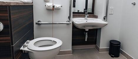 A modern bathroom with a toilet, sink, and hand dryer.