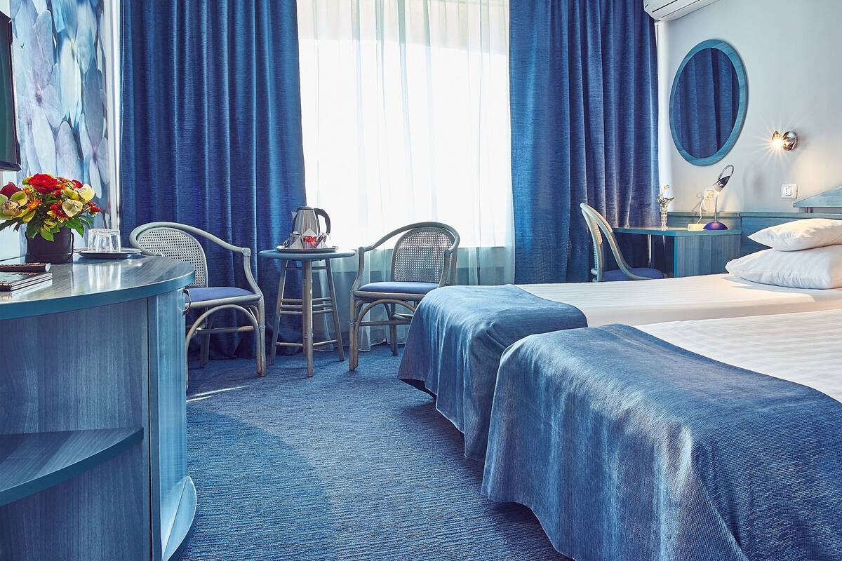 Une chambre d’hôtel avec un lit, deux chaises, un bureau et une petite table.