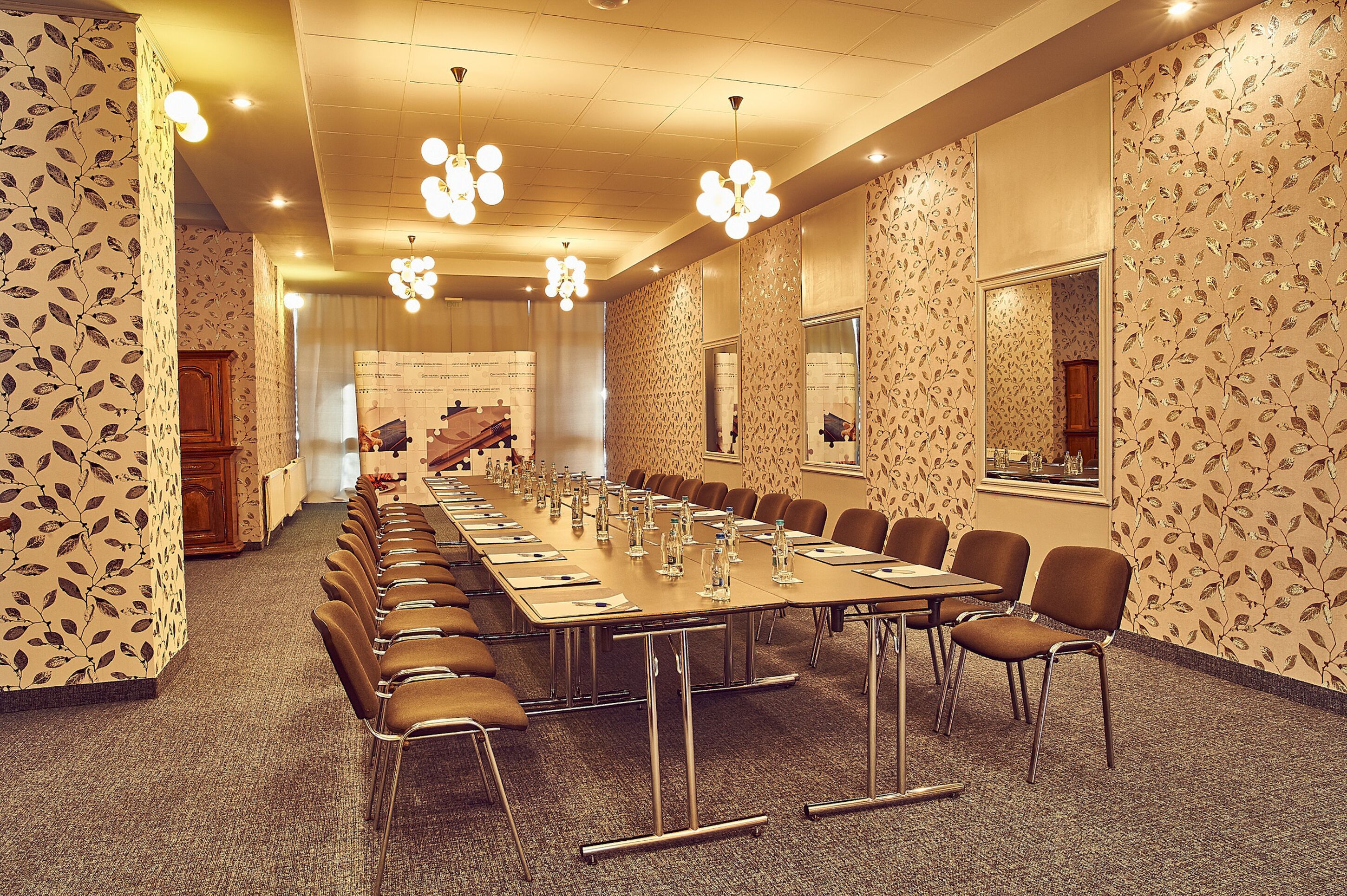 A conference room with a long table, chairs, and a carpeted floor.