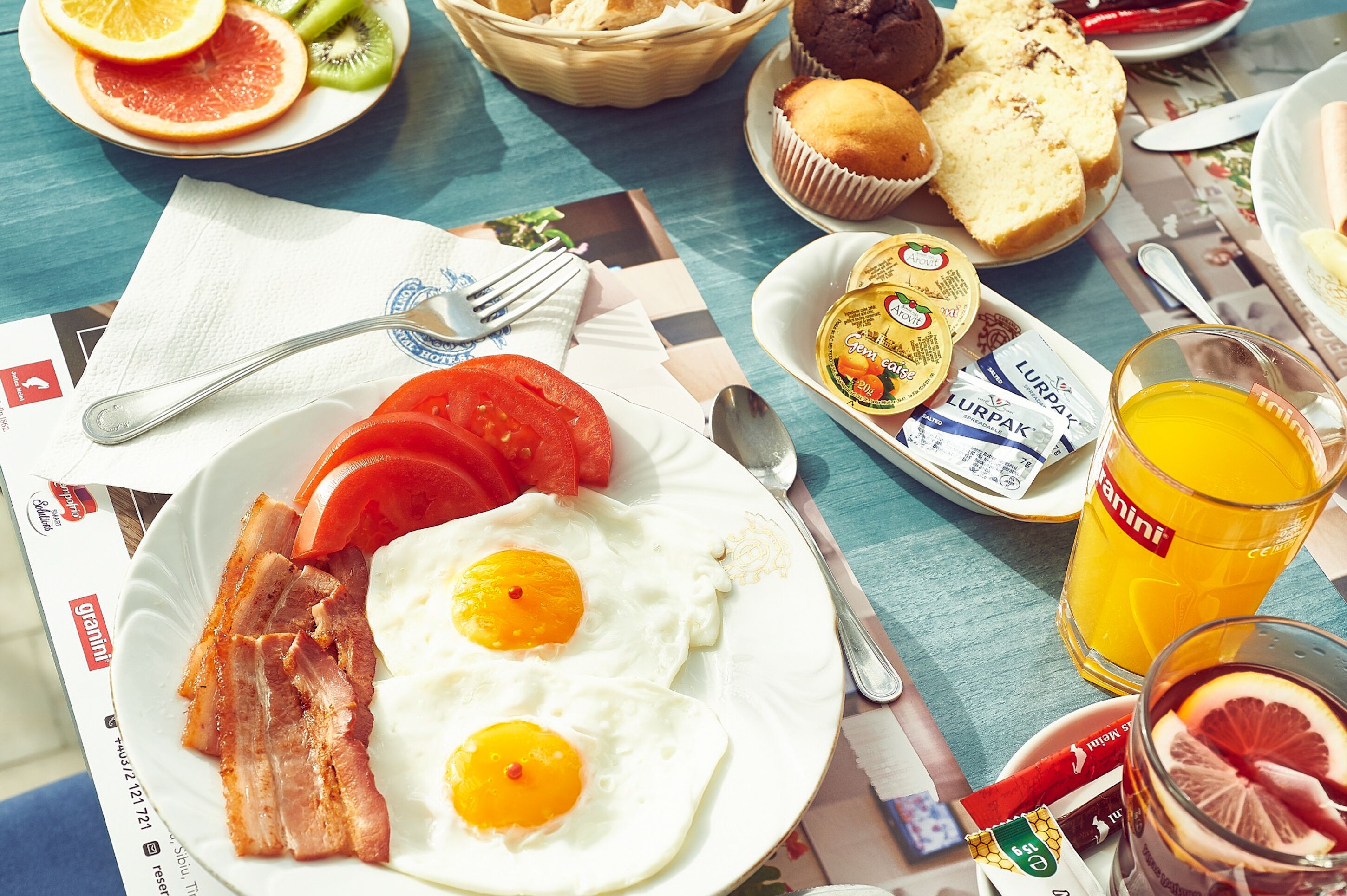 Une table de petit-déjeuner avec des œufs, du bacon, des toasts et un verre de jus d’orange.