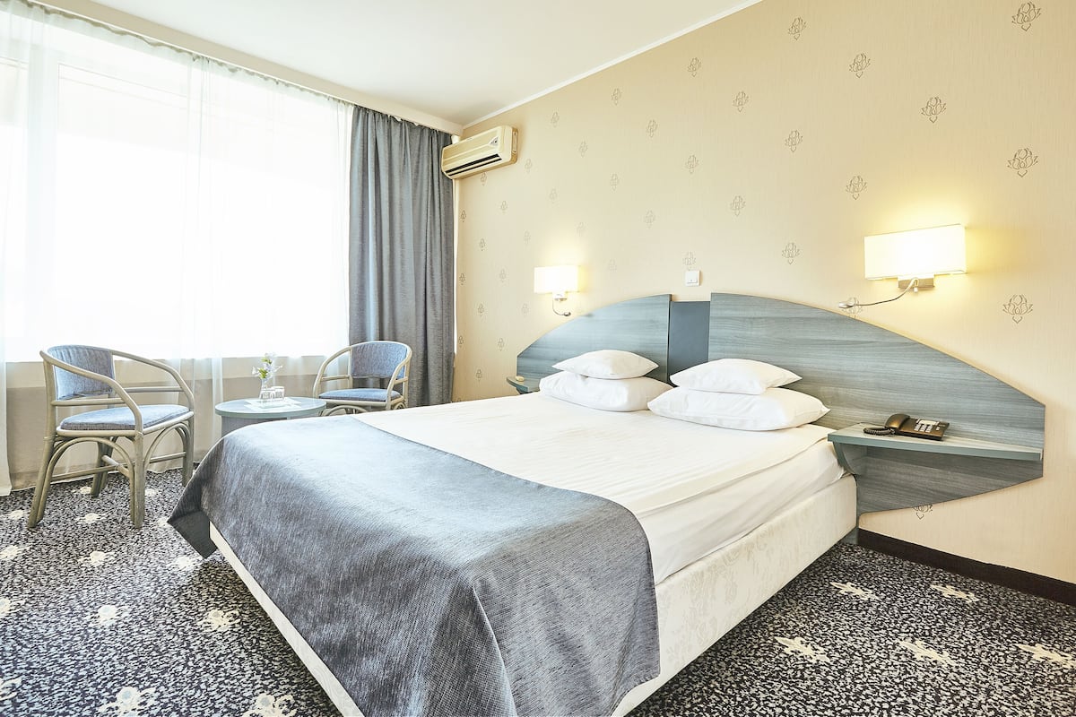 Une chambre d’hôtel avec un grand lit, deux tables de chevet, une chaise et un bureau.