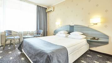 Een hotelkamer met een groot bed, twee nachtkastjes, een stoel en een bureau.