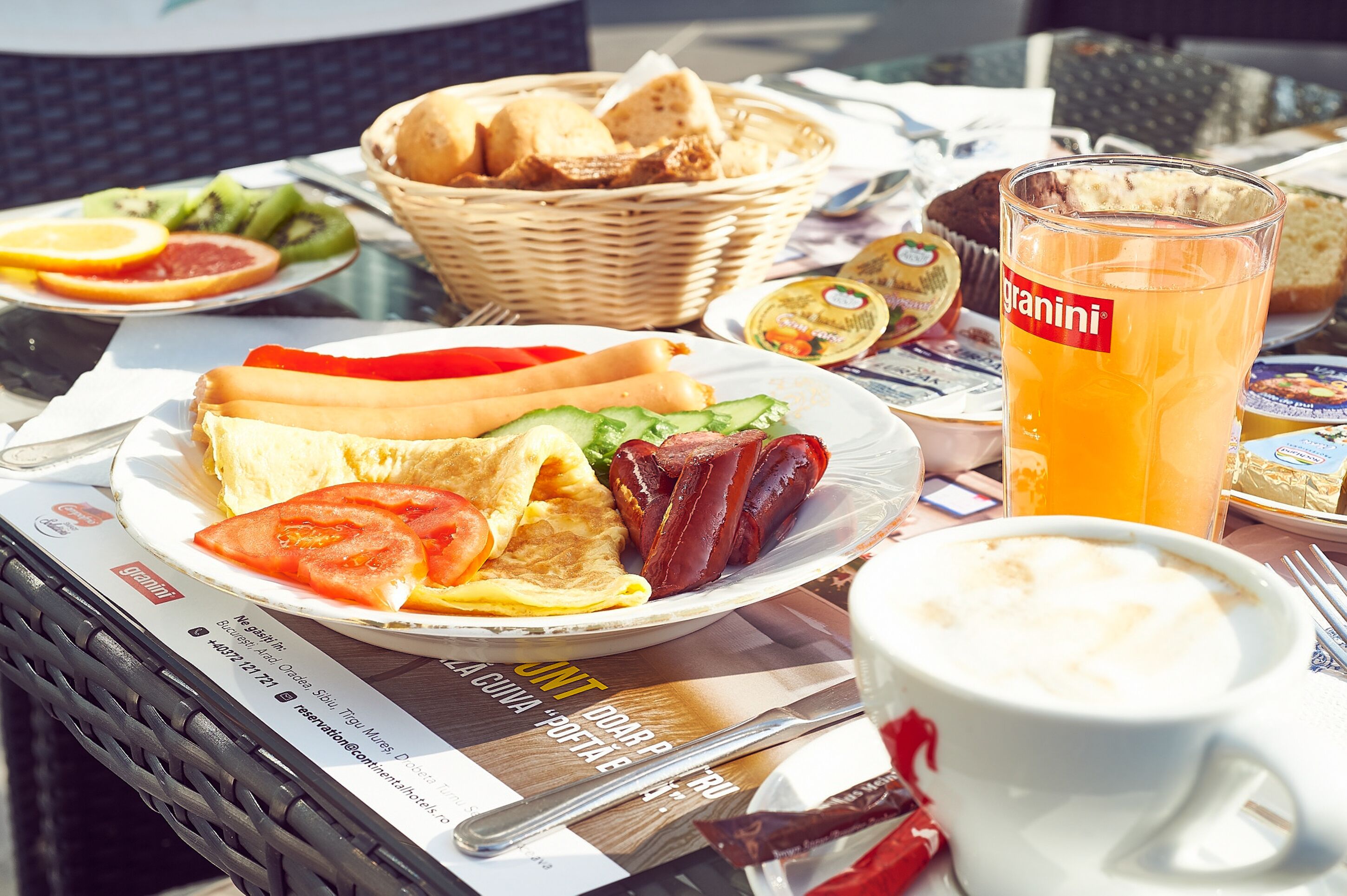 A breakfast setting with a plate of food, a glass of orange juice, and a menu.