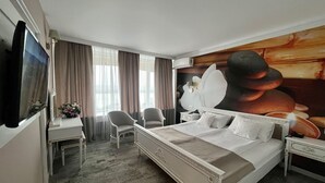 Een hotelkamer met een groot bed, een bureau, twee stoelen, een televisie en een muurschildering.