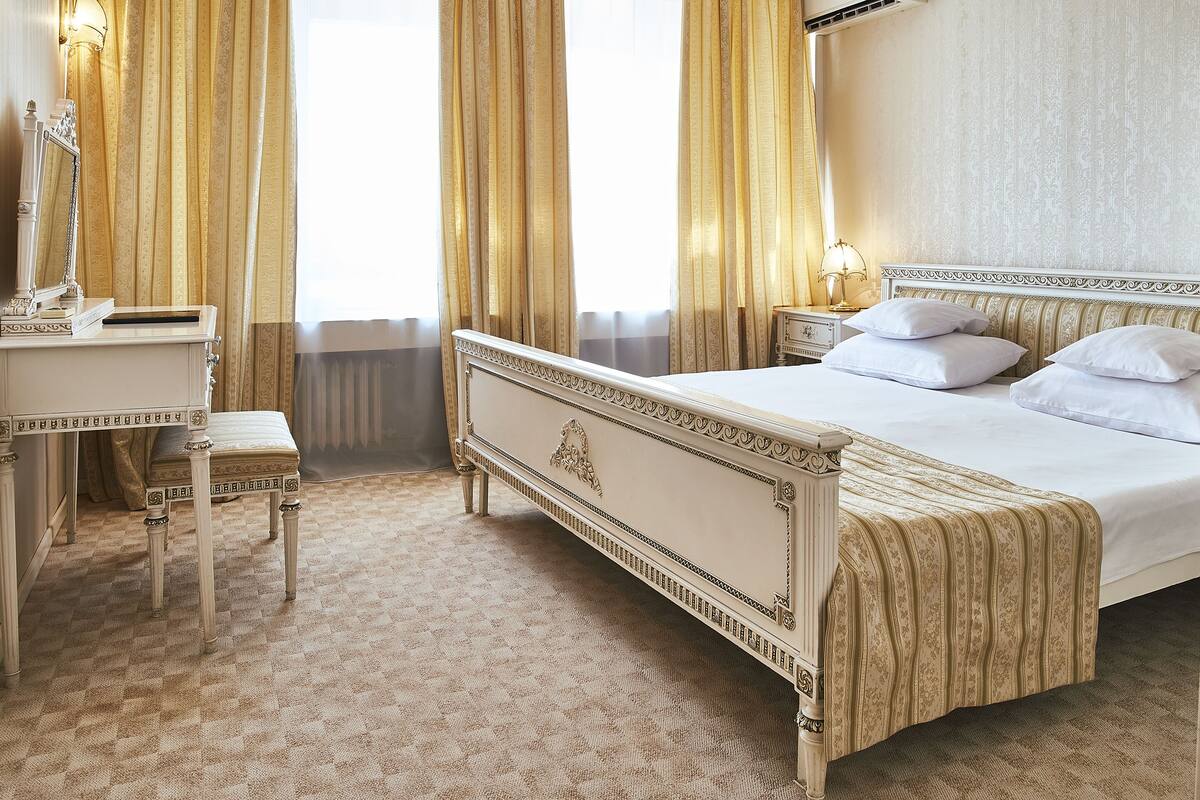 Une chambre d’hôtel classique, dotée d’un grand lit, d’une table de chevet, d’un bureau et d’une chaise.
