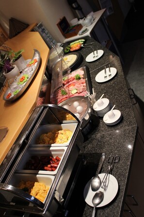 Un buffet proposant une variété de plats et d’ustensiles.