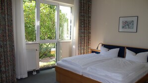 Une chambre avec un grand lit, une fenêtre avec des rideaux, un radiateur et un tableau encadré au mur.