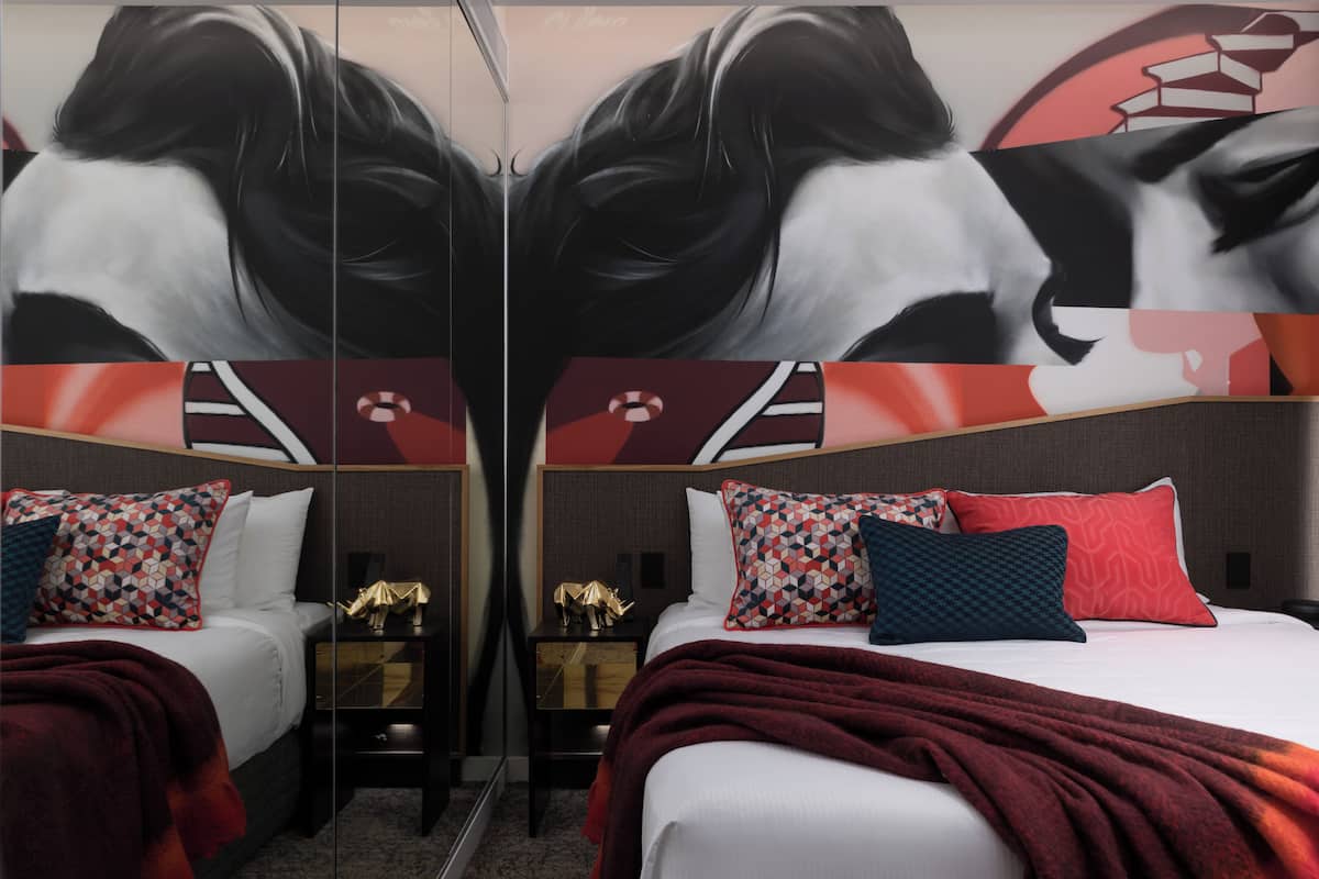 A mirrored room with a bed, pillows, and a nightstand.