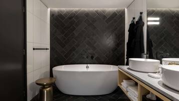 Un baño moderno con una bañera independiente, un tocador con lavabo y un espejo.