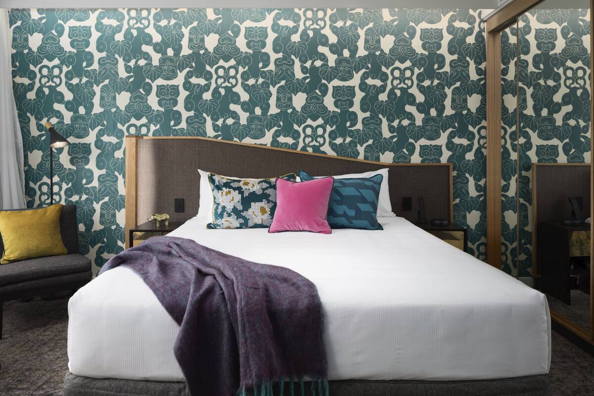 A neatly made bed with a white mattress and multiple pillows in various colors.
