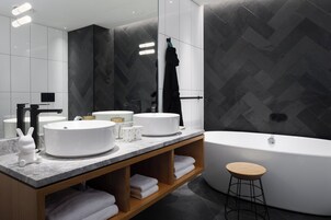 A modern bathroom with two sinks, a bathtub, and a vanity with shelves.