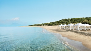 Une plage avec une eau cristalline, des tentes blanches et des chaises longues.