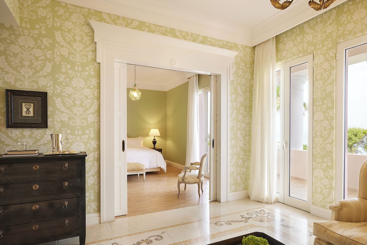 A hotel room with a bed, a desk, a chair, and a view of the outside.