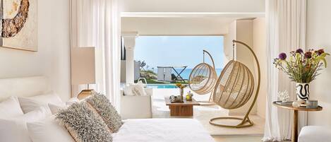 Une chambre spacieuse avec un grand lit, un fauteuil suspendu et une vue sur une piscine et l’océan.