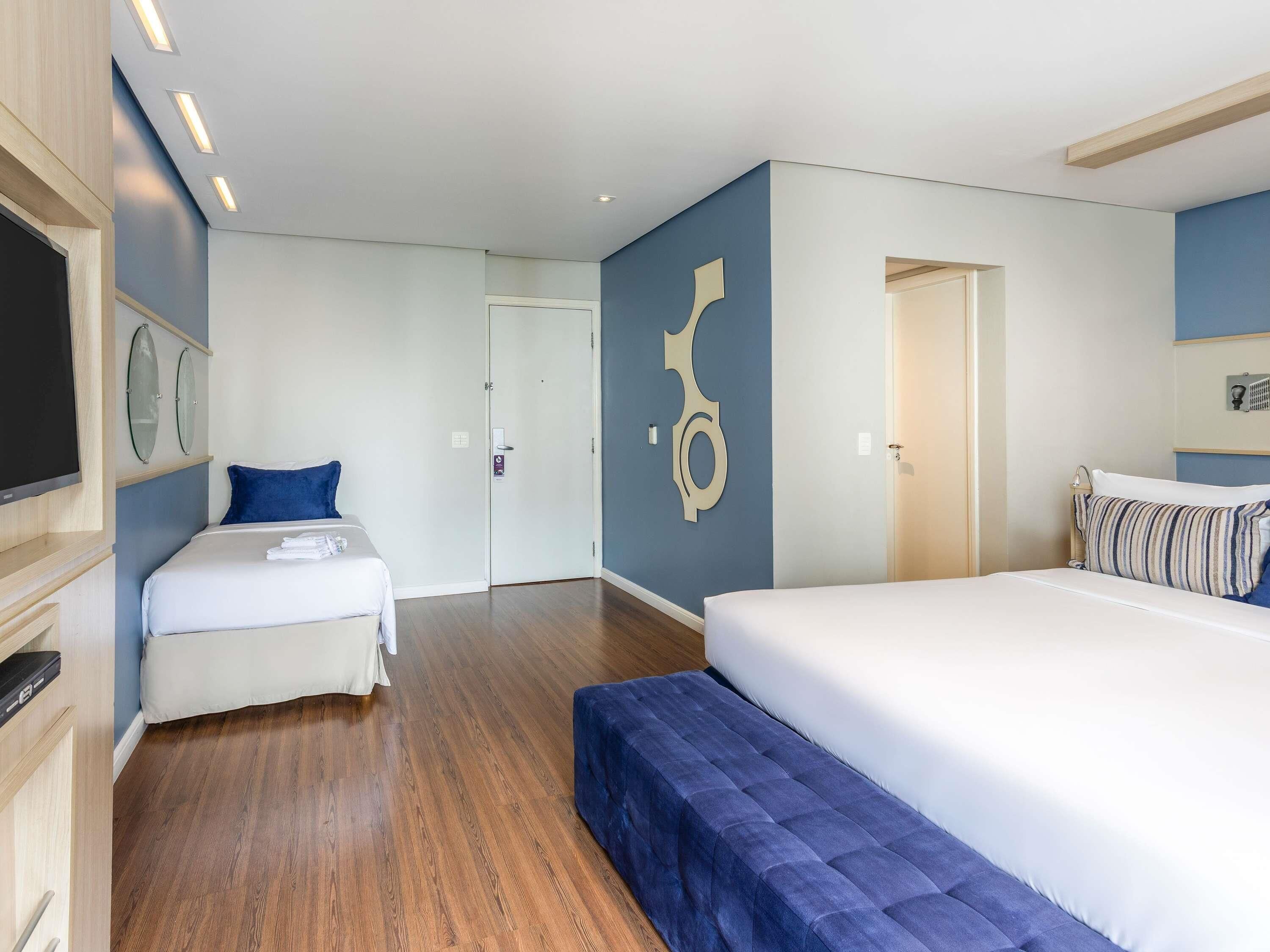 A hotel room with a bed, a sofa, a TV, and a door.
