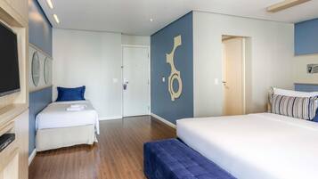A hotel room with a bed, a sofa, a TV, and a door.