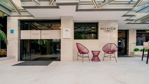 A modern hotel entrance with glass doors, two red chairs, and a sign for 'BOULANGERIE CARIOCA.' - Mercure Sao Paulo Pamplona Hotel (São Paulo)