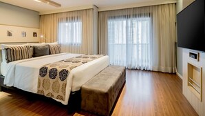 A modern hotel room with a large bed, a bench, a flat-screen TV, and large windows with curtains. - Mercure Sao Paulo Pamplona Hotel (São Paulo)