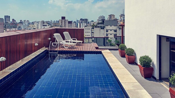Una piscina al terrat amb vistes a la ciutat, gandules i plantes en testos.