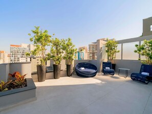 A rooftop terrace with potted plants, a round seating area, and a view of the cityscape. - Mercure Sao Paulo Pamplona Hotel (São Paulo)