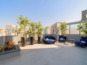 Une terrasse sur le toit agrémentée de plantes en pot, un espace salon circulaire et une petite table.
