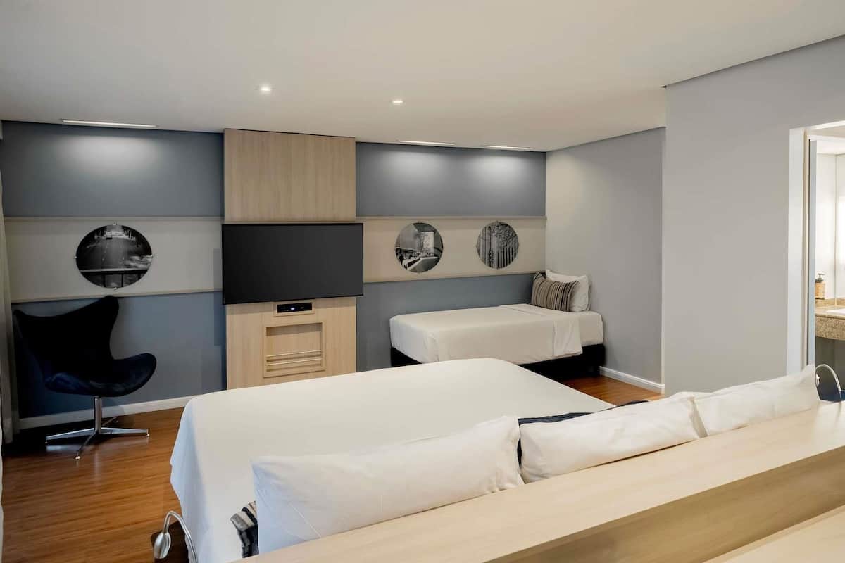 Un dormitorio moderno con una cama grande, otra más pequeña, un televisor y una silla.