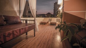 A balcony with a wooden floor, a bed with a canopy, and potted plants. - Reaksmey Chanreas Hotel (Siem Reap)
