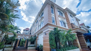 A large, multi-story building with a symmetrical facade, large windows, and a satellite dish on the roof. - Reaksmey Chanreas Hotel (Siem Reap)